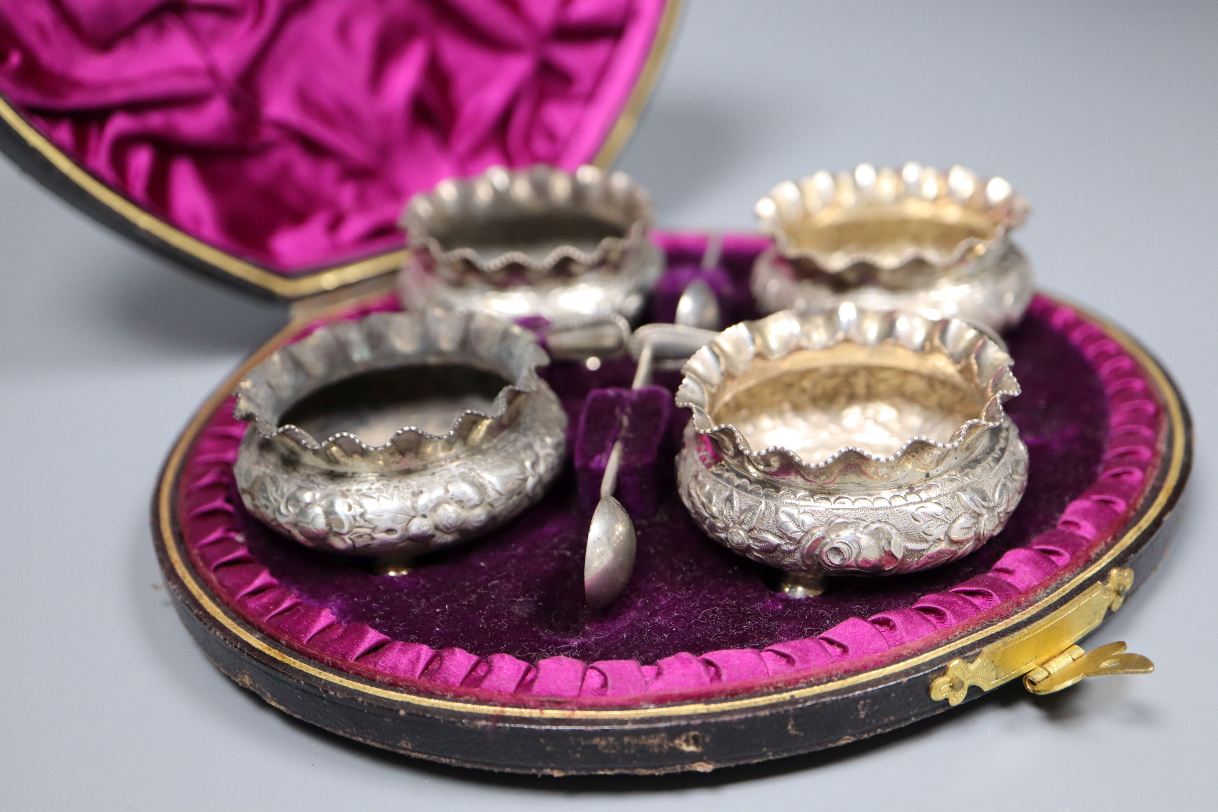 A cased set of four Victorian silver circular salts, Birmingham, 1886 and four spoons.